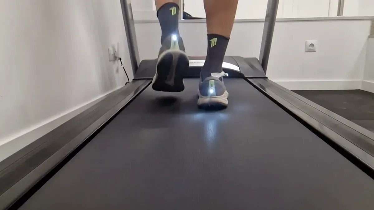 Zapatillas de un corredor vistas por detrás en la cinta, con una luz en el talón para ver cómo gira el tobillo al apoyar